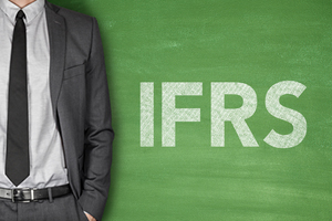 A picture of a business man standing in front of a chalkboard that says IFRS