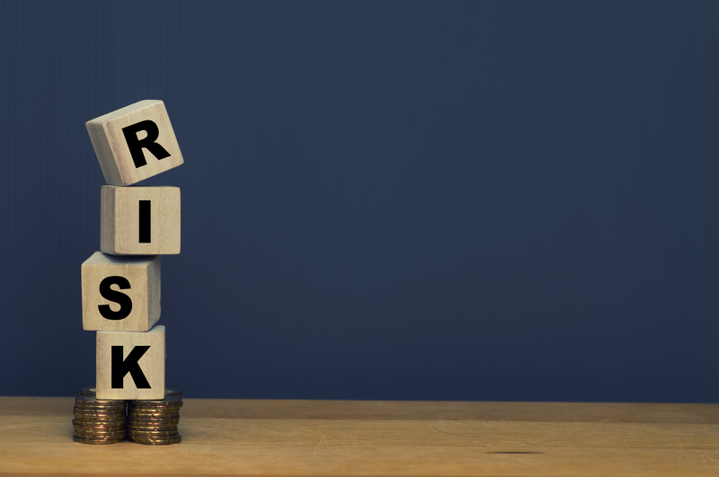 Wooden blocks spelling RISK sitting atop coins