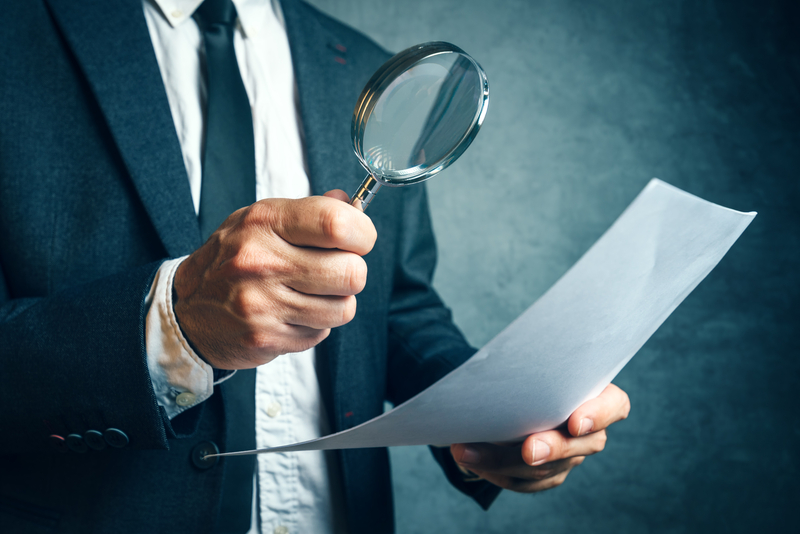 Man examining a report with a magnifying glass