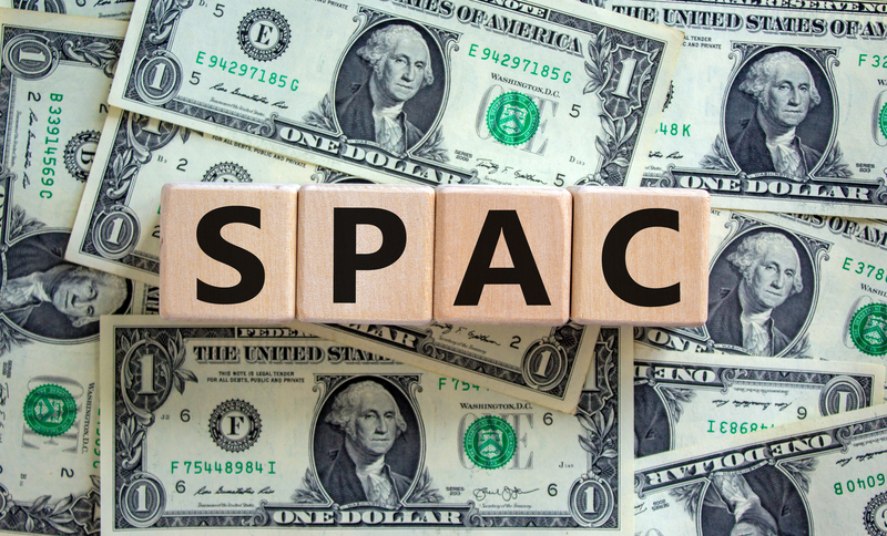 Wooden cubes with word `SPAC` on background made of dollar bills.
